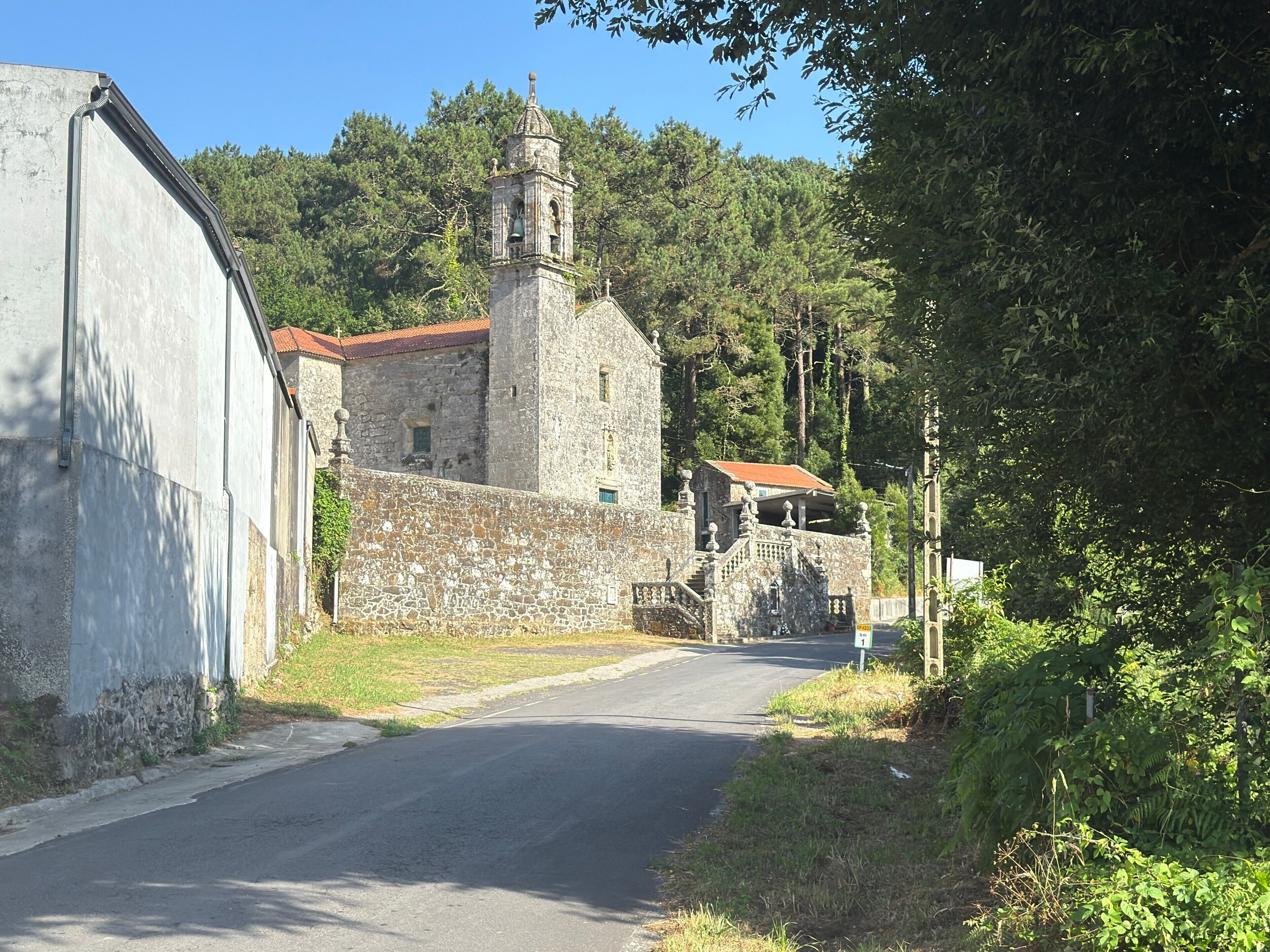 Ein Steinhaus mit einem Glockenturm, einer Treppe und einer Straße, die darauf führt.