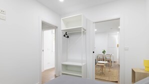 A modern room with a bed, a desk, and a chair. There are white walls and a wooden floor. - Ría De San Cosme María Apartment with Mountain Views, Shared Garden & Air Conditioning (San Cosme-Outes)