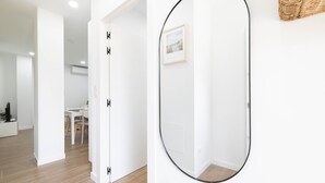 A modern interior with a white door, a dining area with a table and chairs, and a framed picture on the wall. - Ría De San Cosme María Apartment with Mountain Views, Shared Garden & Air Conditioning (San Cosme-Outes)