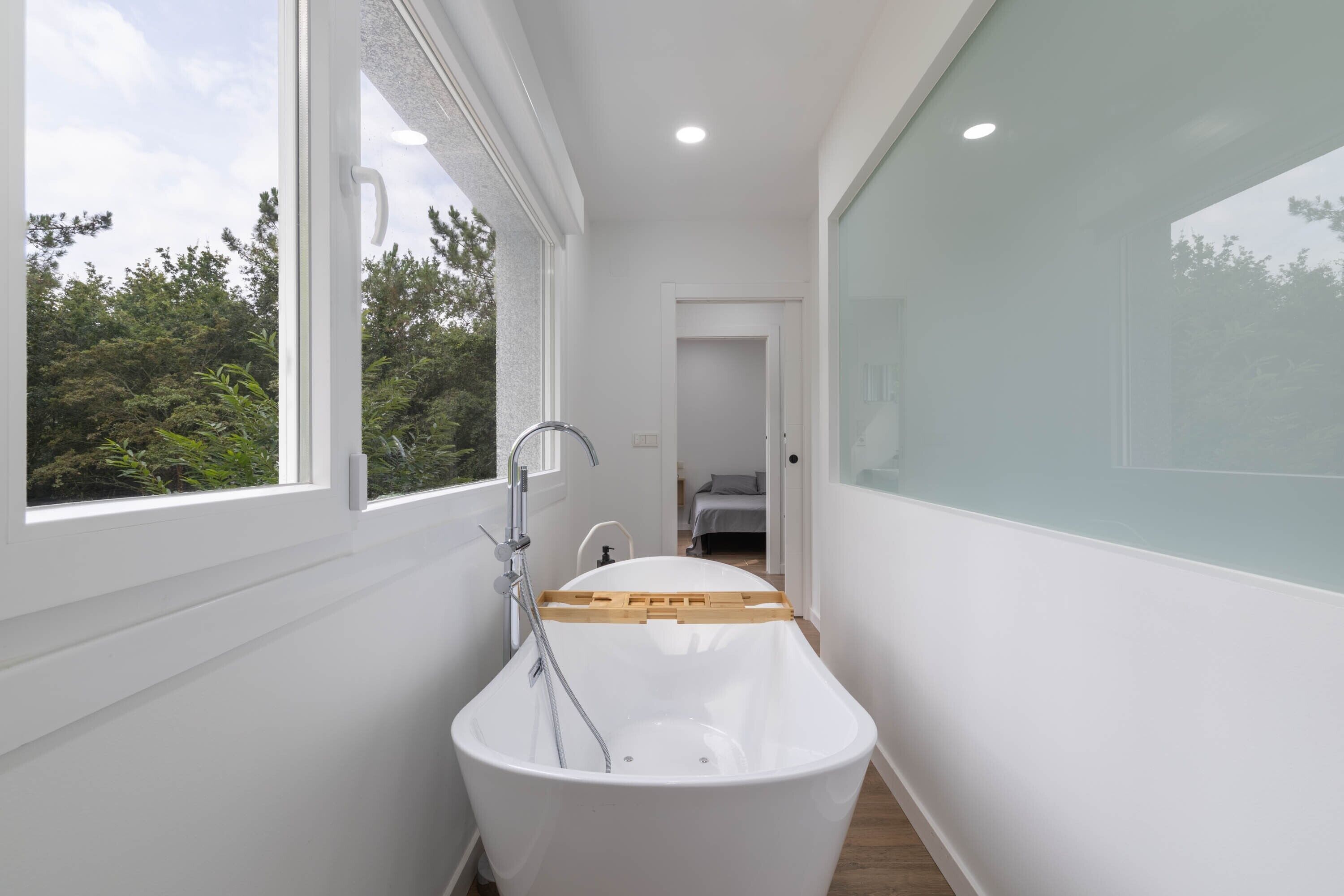 Un baño moderno con una bañera independiente, una ventana y vistas al exterior.