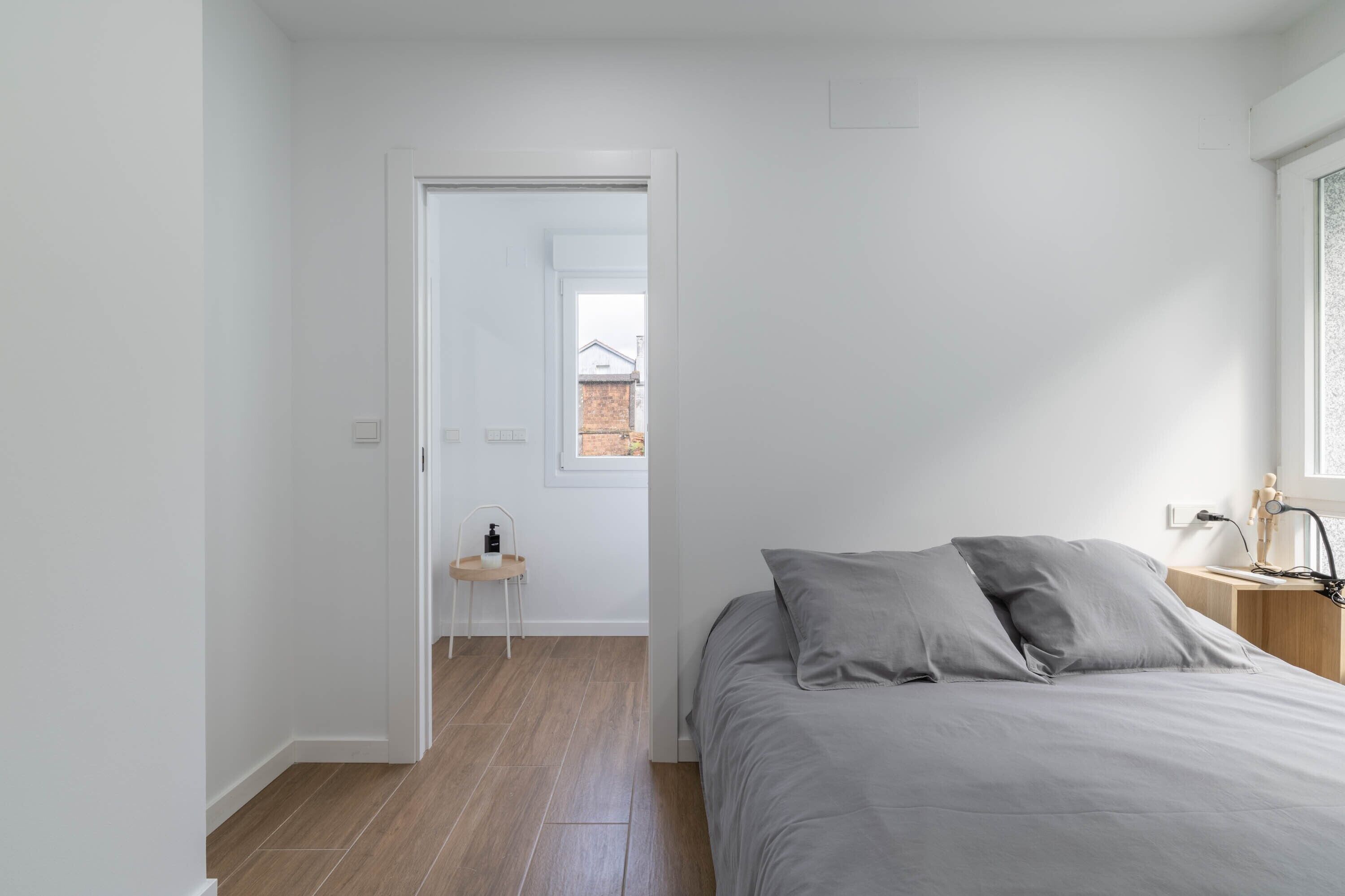 Une chambre à coucher avec un lit, une table de chevet, une lampe et une fenêtre.