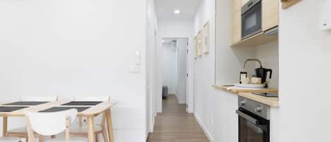 A modern kitchen with a microwave, oven, and wooden cabinets. There is a dining area with a table and chairs.