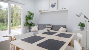 Habitació moderna amb taula de menjador, sofà i una planta.