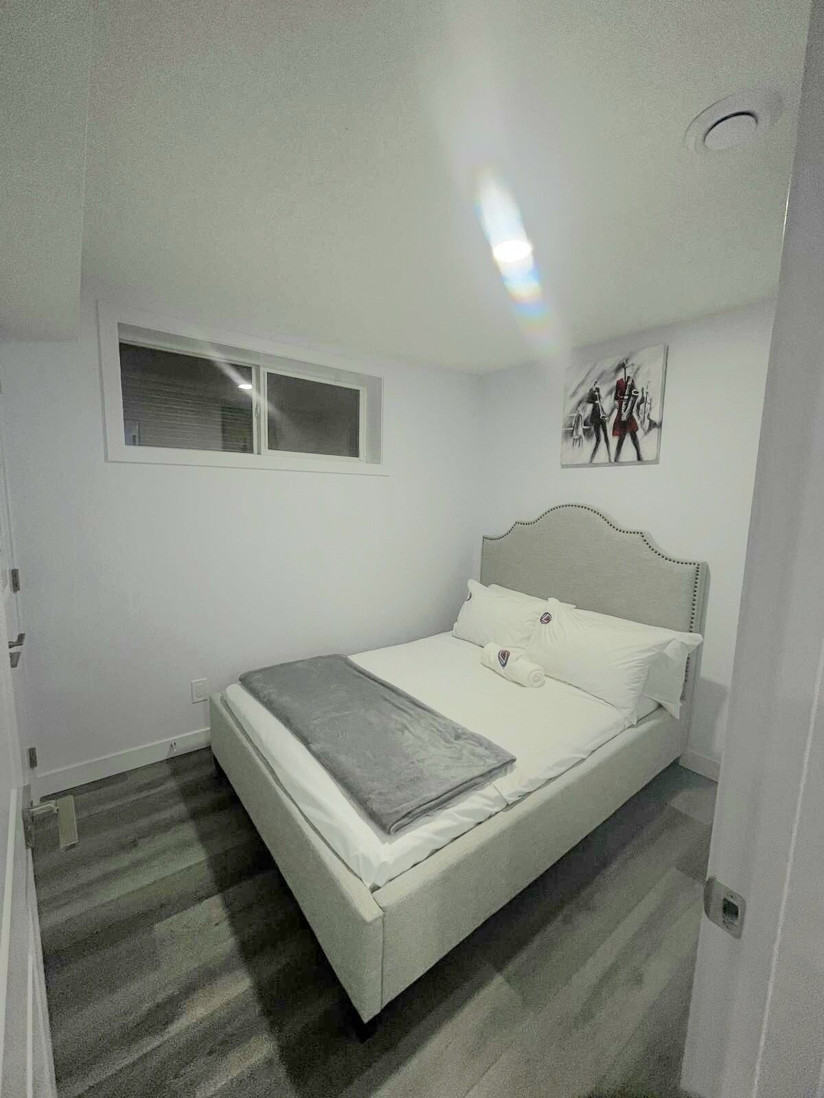 Une chambre avec un lit simple, une fenêtre et un tableau au mur.