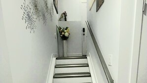 A staircase with a handrail, white walls, and a door at the top. - Discover your ideal getaway. Relax and recharge in a space that feels like home. (Edmonton)