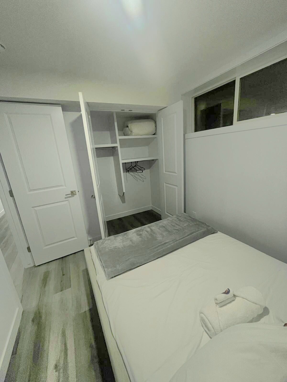 Un dormitorio pequeño y acogedor con una cama individual, un armario con espacio para colgar ropa y una ventana.