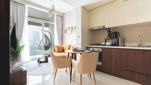 A modern kitchen with a dining area, a hanging chair, and a view of the city. - Keyrock Living - 1BR Lake View at Reva (Dubai)