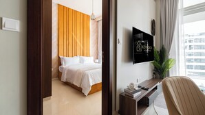 A modern hotel room with a bed, a desk, and a TV. - Keyrock Living - 1BR Lake View at Reva (Dubai)