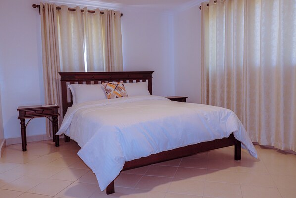 A neatly made bed with a wooden headboard and two nightstands, one with a lamp.