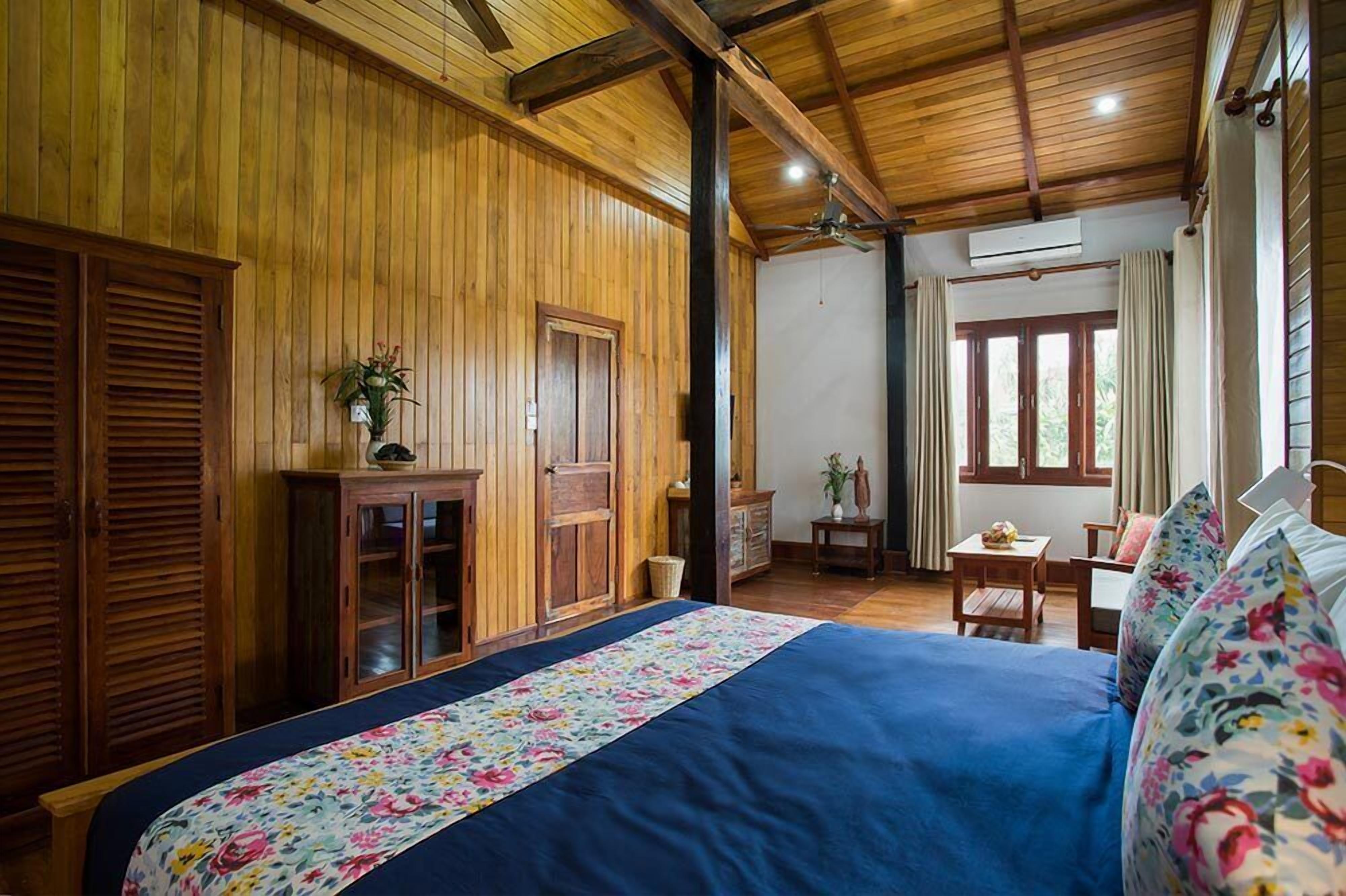 Una habitación con paneles de madera, una cama, una mesita y una silla.