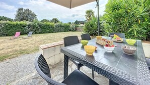 An outdoor patio with a table set for dining, surrounded by chairs and an umbrella.