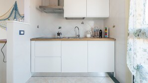 A modern kitchen with white cabinets, a stainless steel range hood, a sink, and a coffee machine. - Mare Fuori by Interhome (Villasimius)