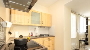 A modern kitchen with wooden cabinets, a black induction cooktop, a kettle, and a sink.