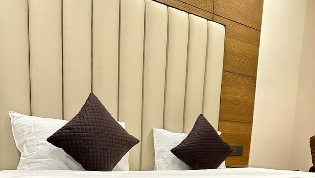 Une chambre d’hôtel avec un lit recouvert d’une courtepointe marron matelassée et agrémenté de deux oreillers, un blanc et un marron.