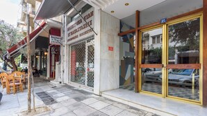 Un edificio con fachada de mármol, una puerta de metal y suelo a cuadros en el exterior.