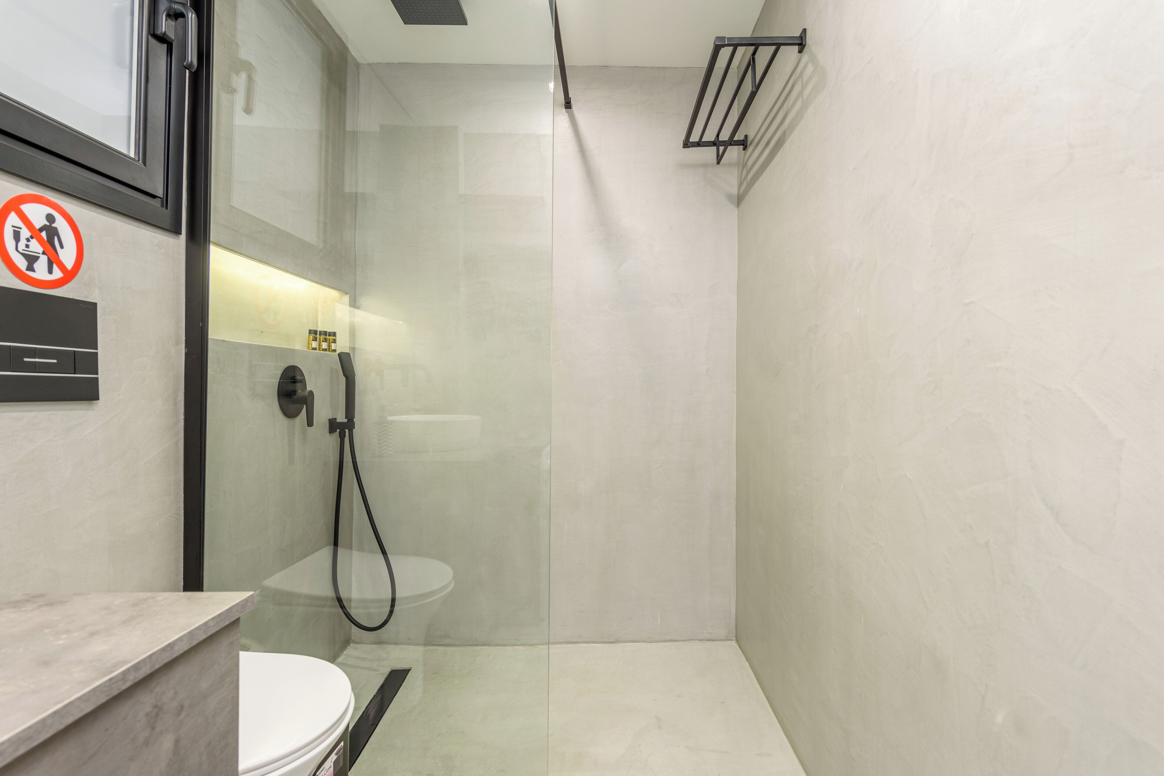 A modern bathroom with a glass-enclosed shower, a toilet, and a sink.
