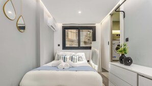 Un dormitorio moderno con cama, cómoda, ventana y espejo.