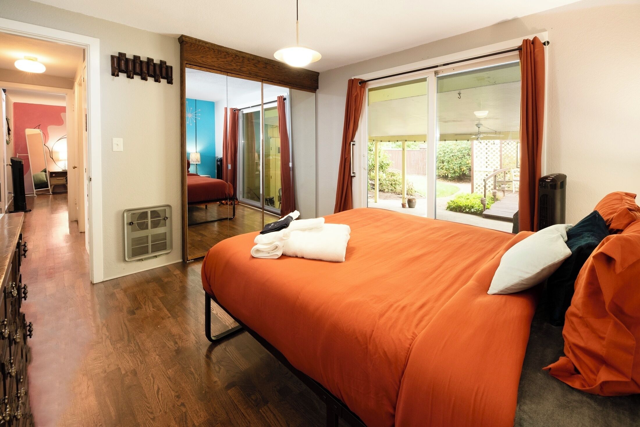 A bedroom with a large bed, a sliding glass door to a balcony, and a visible bathroom.