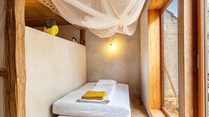 Ein kleiner, gemütlicher Raum mit einem Bett, einem Fenster und einer Wandleuchte.