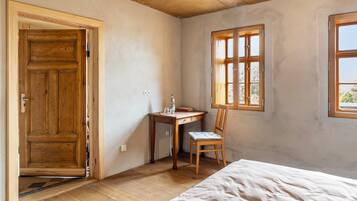 Una habitación con puerta de madera, un escritorio con silla, una cama y una ventana.