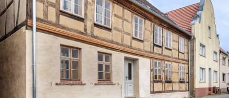 A traditional half-timbered building with a cobblestone street, a door, and windows.