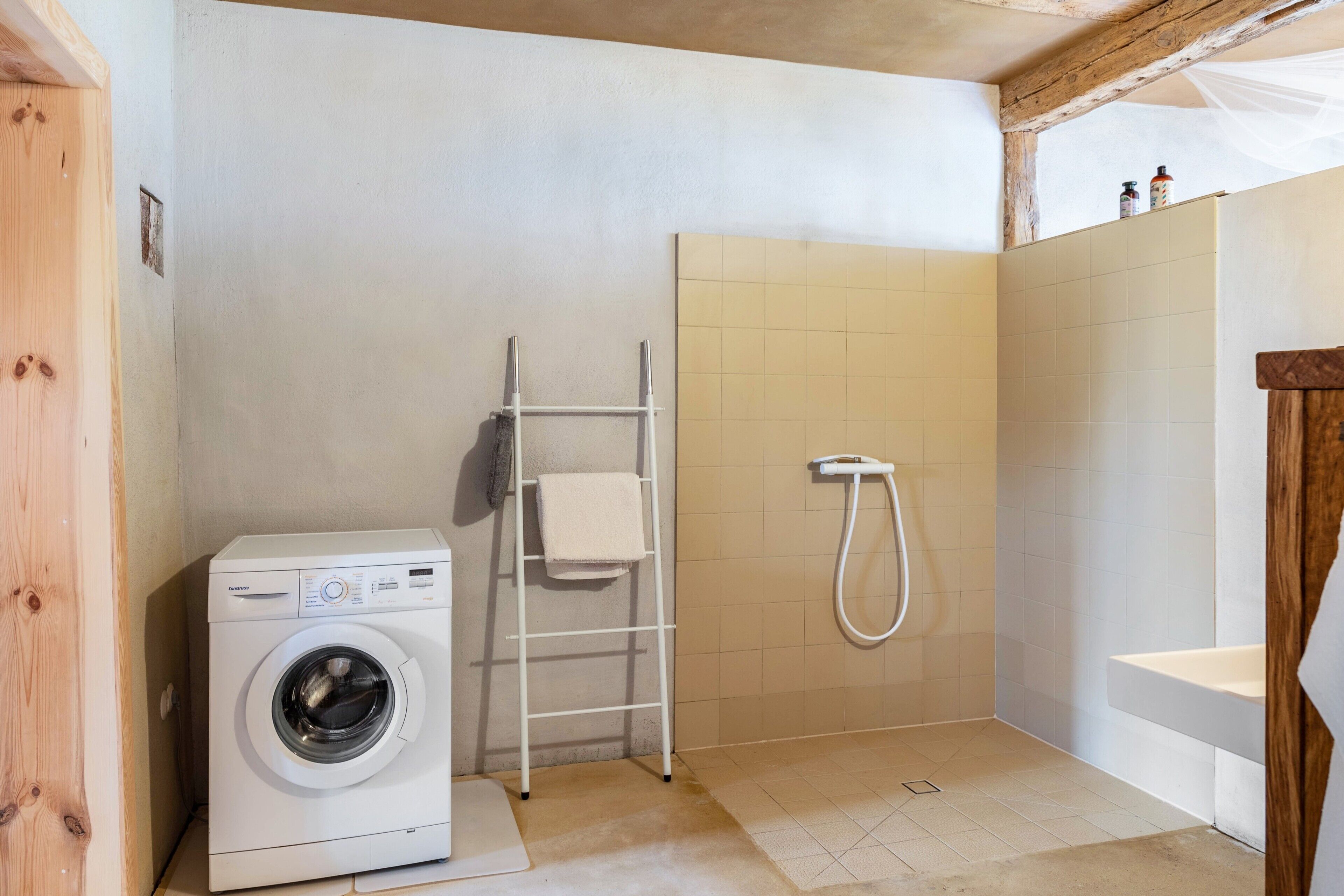 A laundry area with a washing machine, a drying rack, and a shower.
