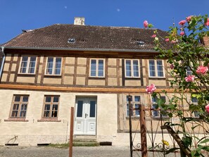 A traditional half-timbered house with a central entrance, multiple windows, and a visible chimney.