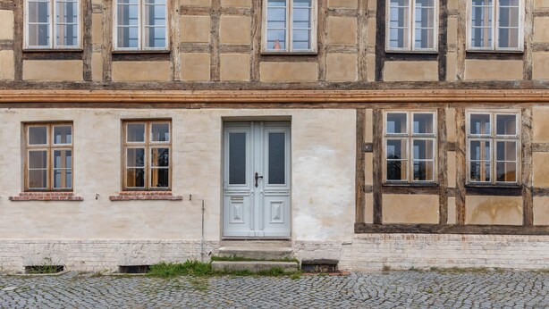 Ein zweistöckiges Gebäude mit einer symmetrischen Fassade, zahlreichen Fenstern und einer zentralen Tür.