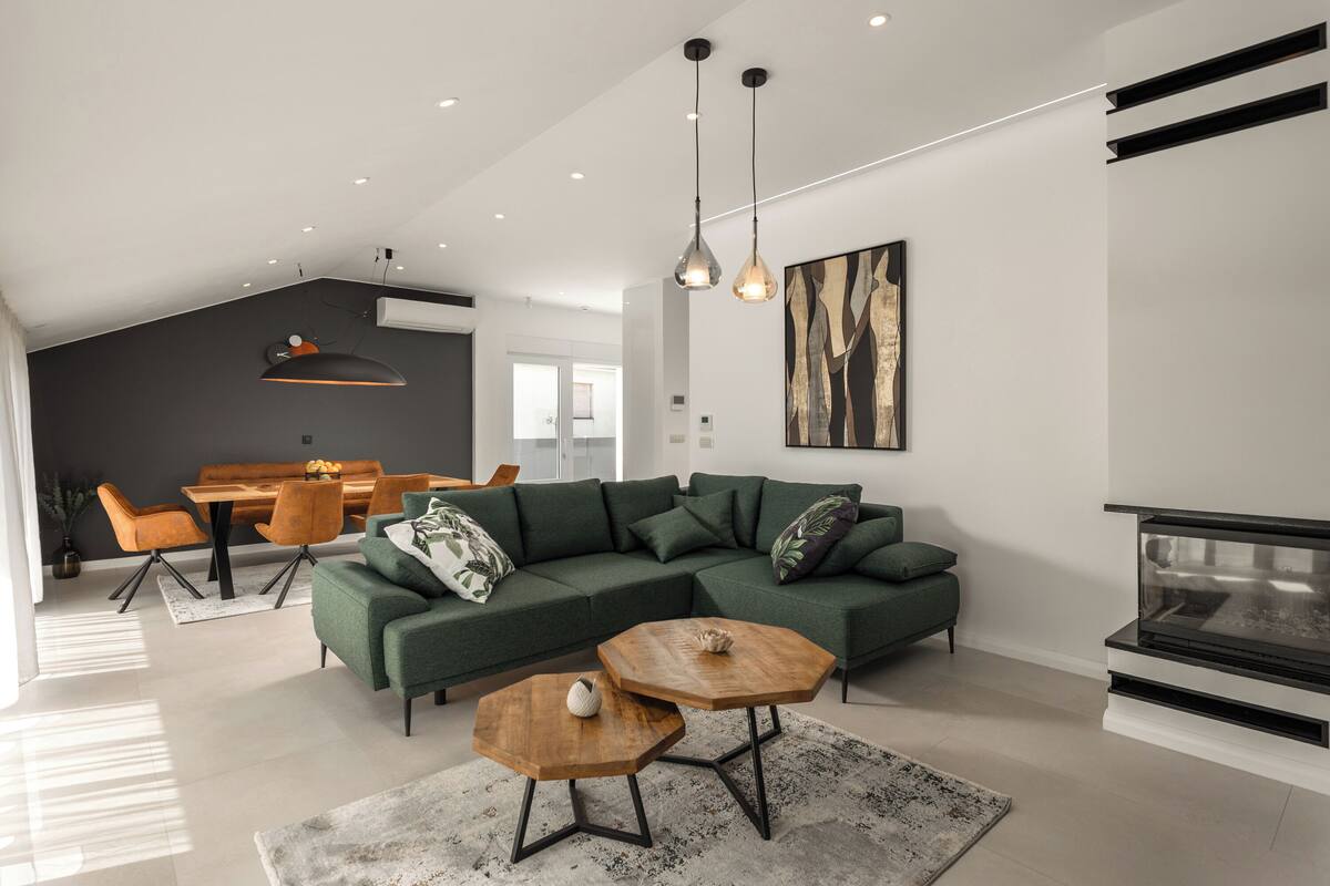 Una sala de estar moderna con un sofá modular, un comedor con mesa y sillas de madera, y una chimenea.