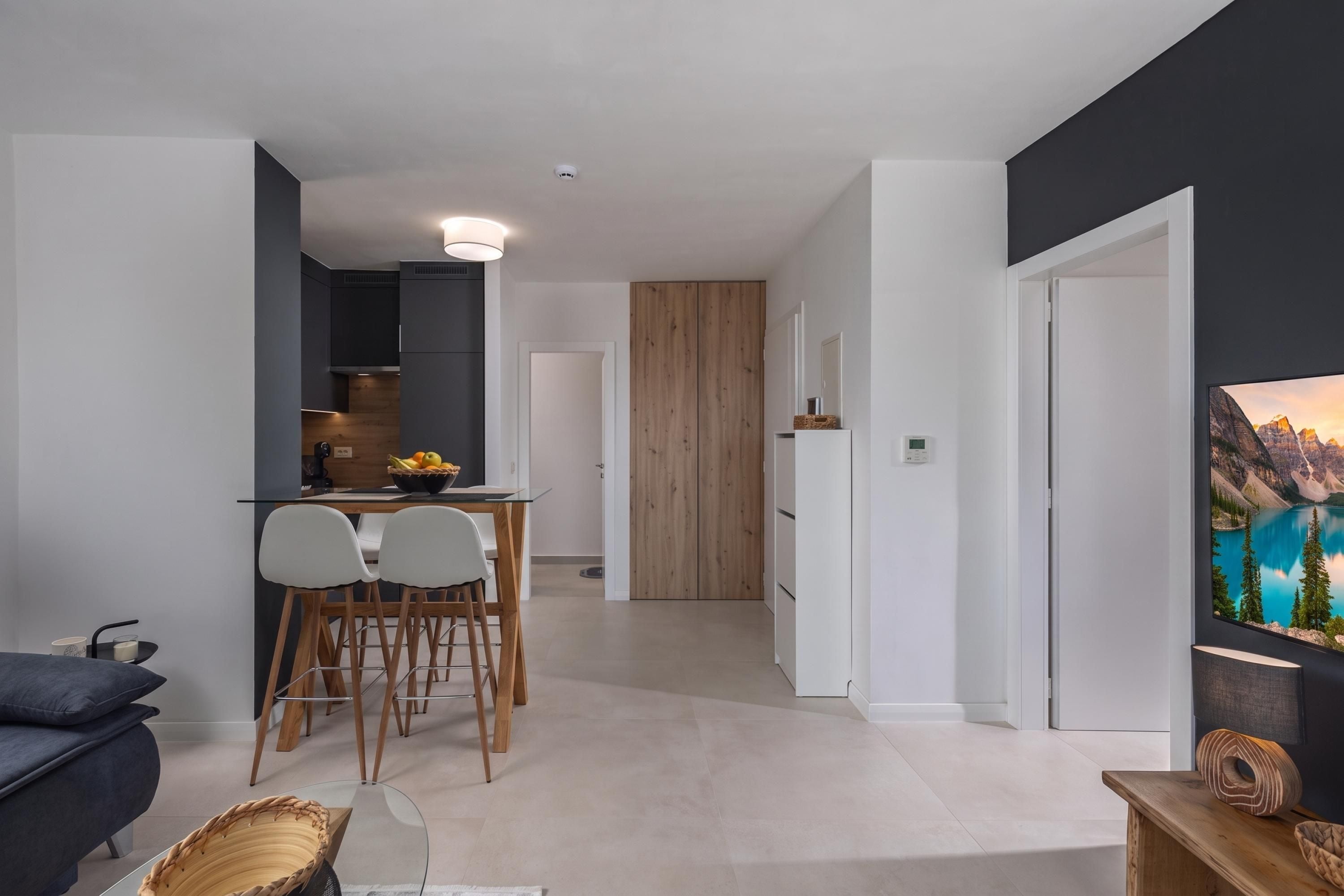 A modern living space with a dining area, kitchen, and a large window with a mountain view.