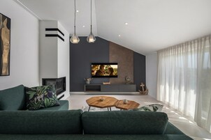 A modern living room with a green sofa, a wooden coffee table, and a flat-screen TV mounted on the wall.