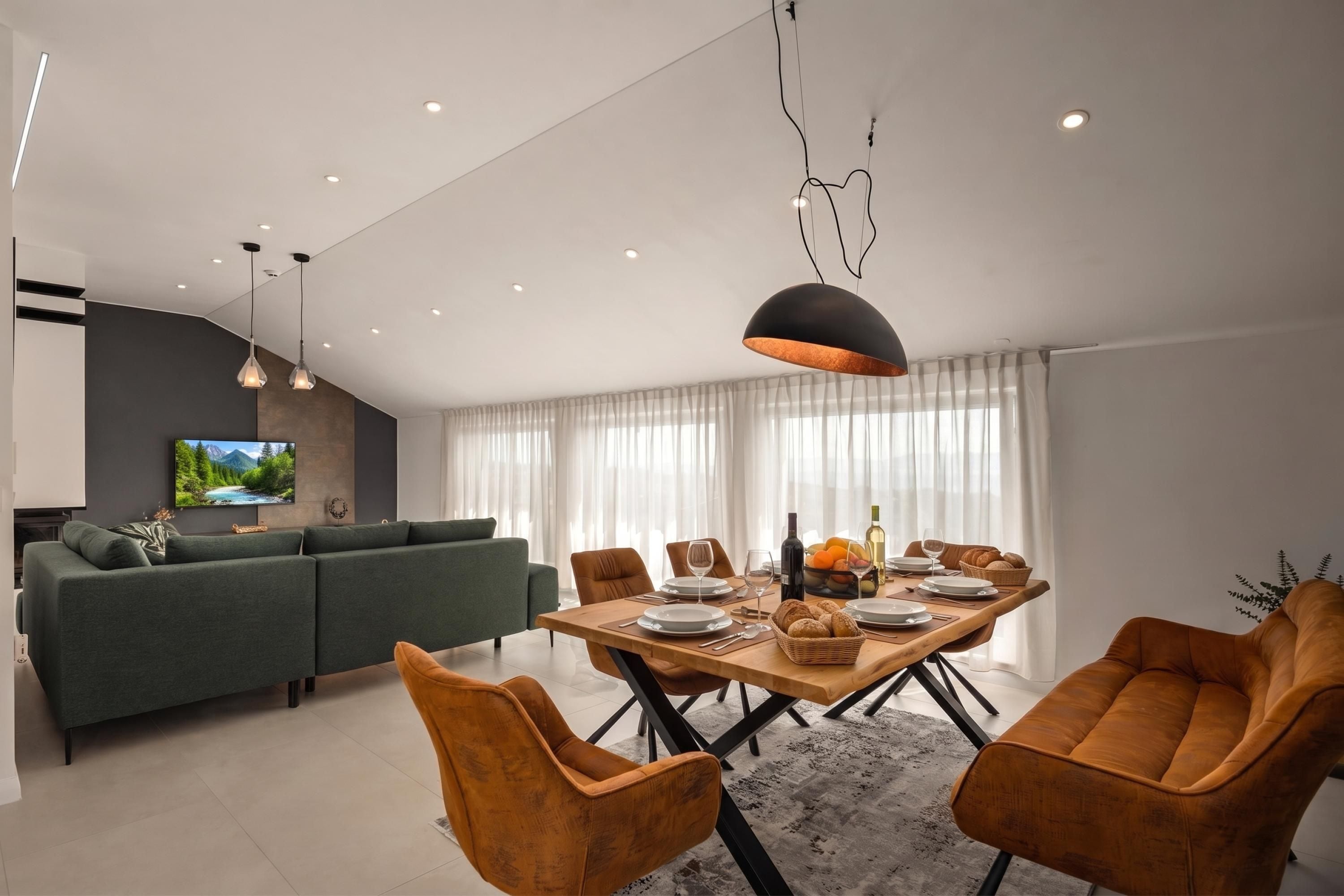 Ein modernes Wohnzimmer mit einer Couch, einem Esstisch, Stühlen und einem Fernseher.