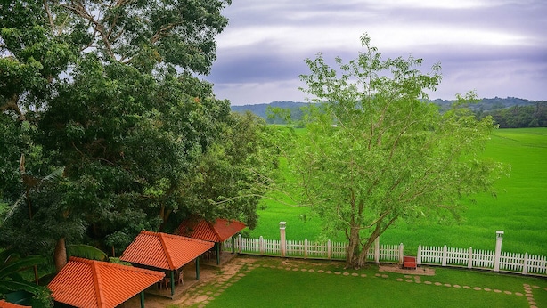 A rural landscape with a gazebo, a white picket fence, and a large tree. - Mami Resort (Tangalle)