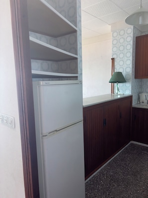 A kitchen with wooden cabinets, a white refrigerator, and a green lamp on the countertop. - Apartment with a dream view in a prime location - Roses (Roses)