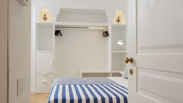 Une chambre à coucher comprenant un lit, une armoire, un bureau et une étagère avec une lampe.
