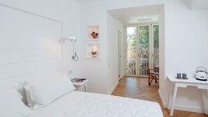 A modern bedroom with a large bed, a bedside table with a kettle, and a view of a balcony. - Tasso 41 House Sorrento City Center (Sorrento)