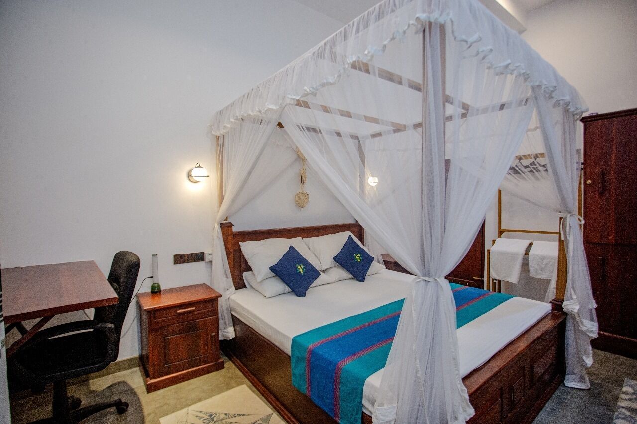 A bedroom with a four-poster bed, a desk, and a chair.