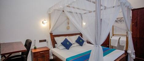 A bedroom with a four-poster bed, a desk, and a chair.