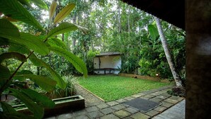 Ein Garten mit einem kleinen Bauwerk, einem befestigten Bereich und üppigem Grün.