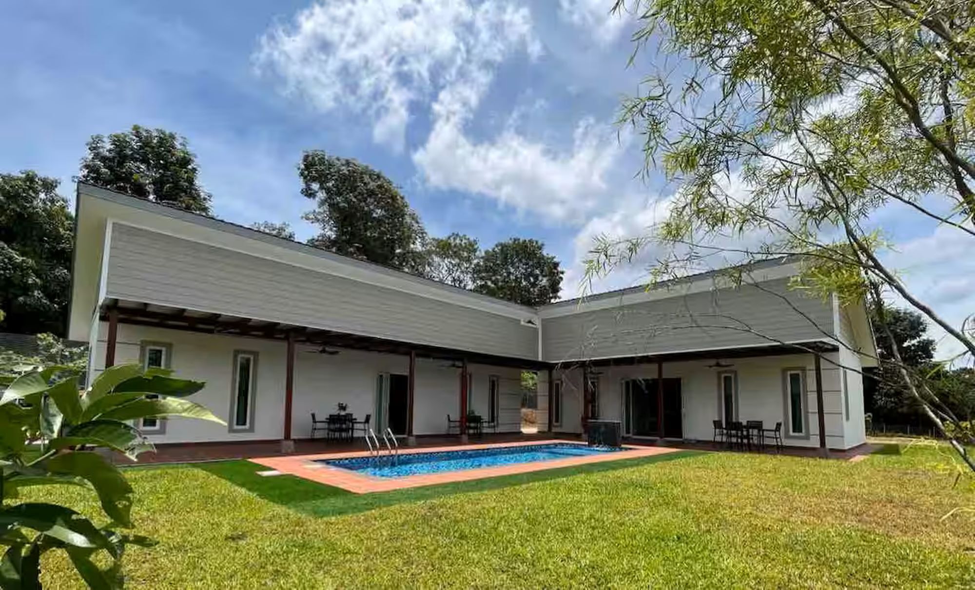 Een huis met twee verdiepingen, een overdekte patio en een zwembad.