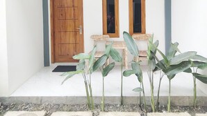 Une entrée propre et moderne, avec une porte en bois, deux fenêtres et une petite table entourée de chaises.