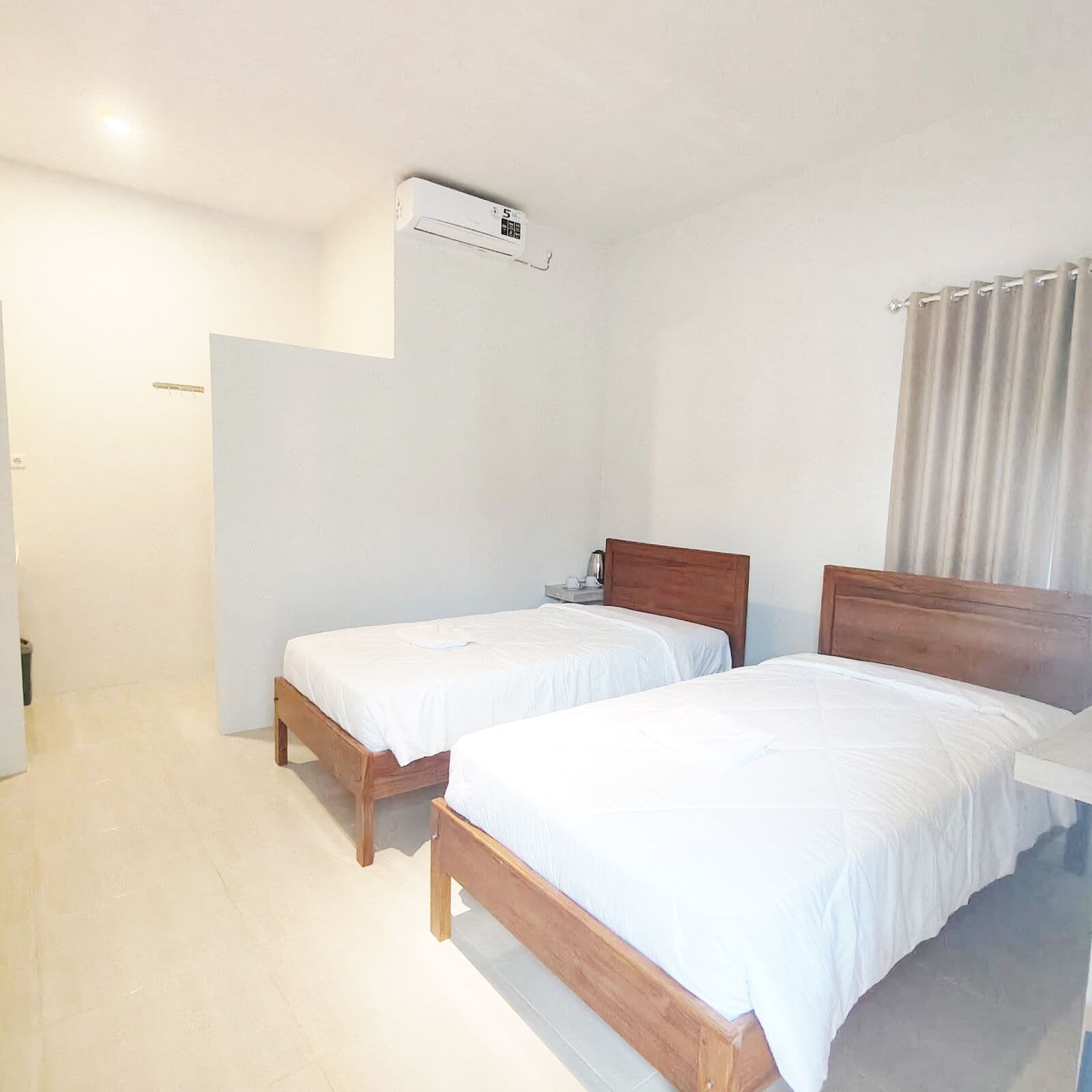 A room with two wooden beds, a white ceiling, and a white wall.