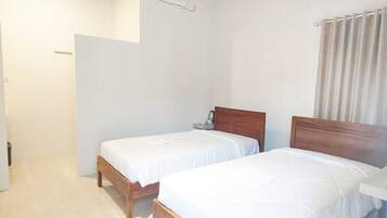 A room with two wooden beds, a white ceiling, and a white wall.