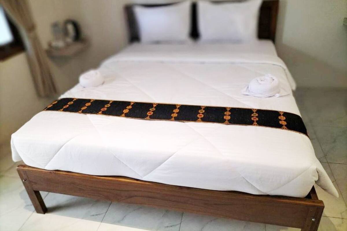 Un letto rifatto con una coperta bianca e una fascia decorativa nera.