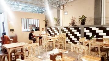Un restaurant avec des meubles en bois, un mur orné d’un motif noir et blanc et des plantes en pot.