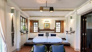 A hotel room with a double bed, two chairs, a wooden headboard, and a large window with a view. - Villa Pateh (Sikao)