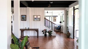 A spacious living area with a wooden bench, a staircase, and a large window. - Villa Pateh (Sikao)