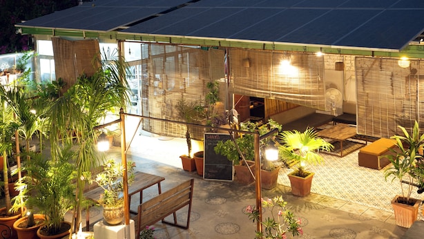 A rooftop terrace with solar panels, potted plants, and outdoor seating.