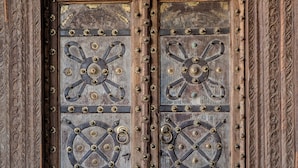 A wooden double door with intricate carvings and metal fixtures.