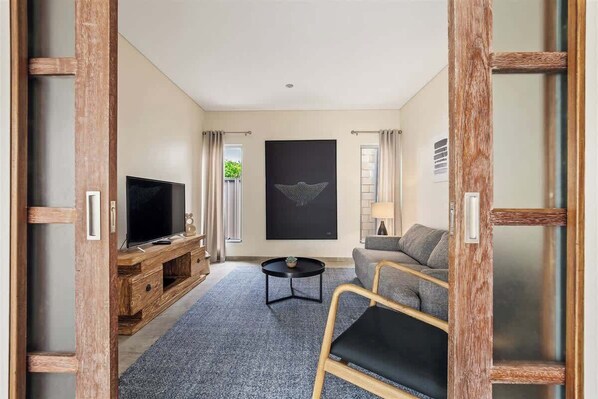 A living room with a TV, sofa, and artwork on the wall.